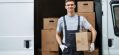 a-young-handsome-smiling-worker-wearing-uniform-is-standing-next-to-the-van-full-of-boxes-holding-a.jpg