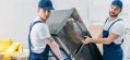 two-movers-in-uniform-using-hand-truck-while-transporting-refrigerator-in-apartment.jpg